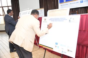 Dr Olaro Charles (Director Health Services) and Dr Allan Muruta (Commisioner IES and PHEs) of Ministry of Health signing during the launch of the National Laboratory Guidelines for Preparedness and Response to Public Health Emergencies
